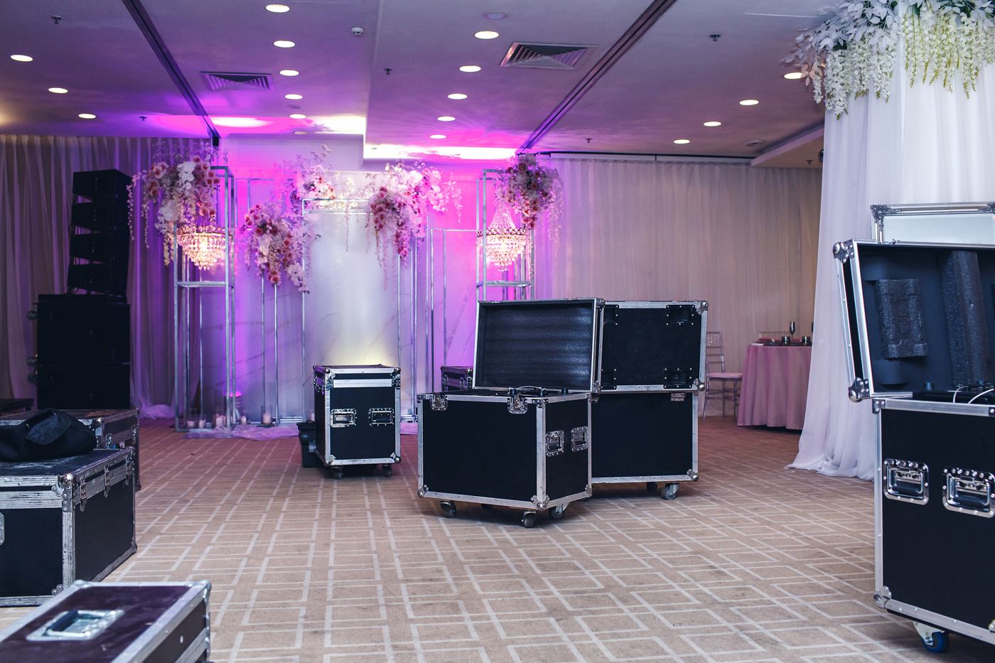 Equipment cases staged on a ballroom floor during load-in, with drape and uplighting behind
