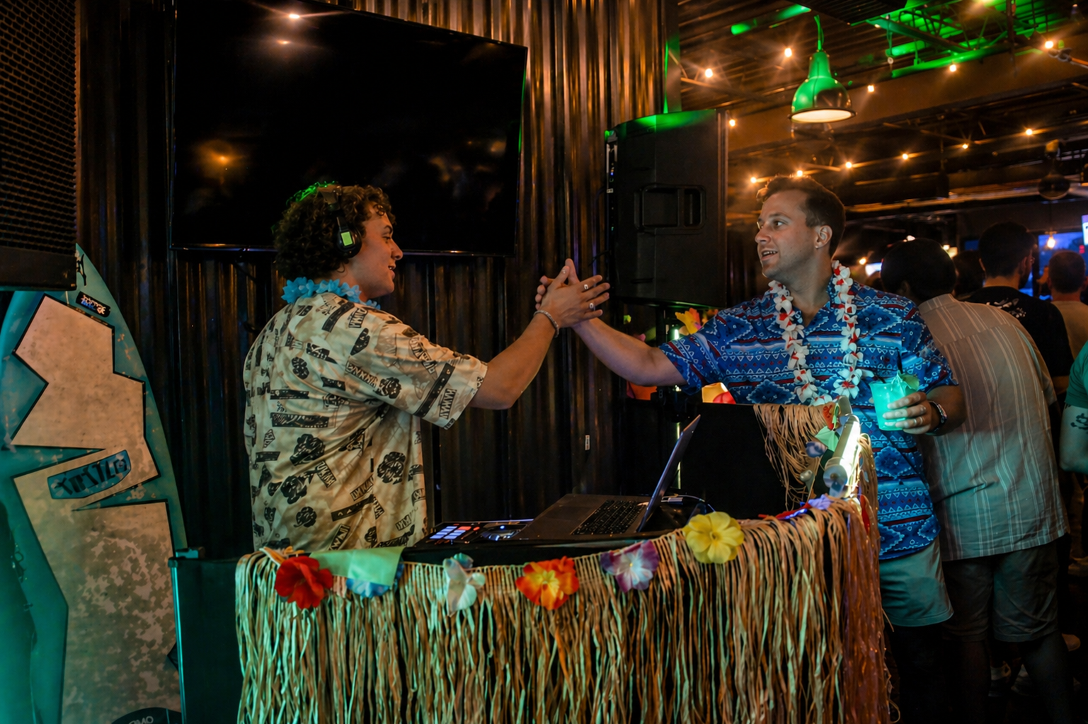 DJ Laki greeting a guest at a tropical tiki-themed private party with custom DJ booth, leis, and ambient lighting &ndash; Atlanta Music Pros