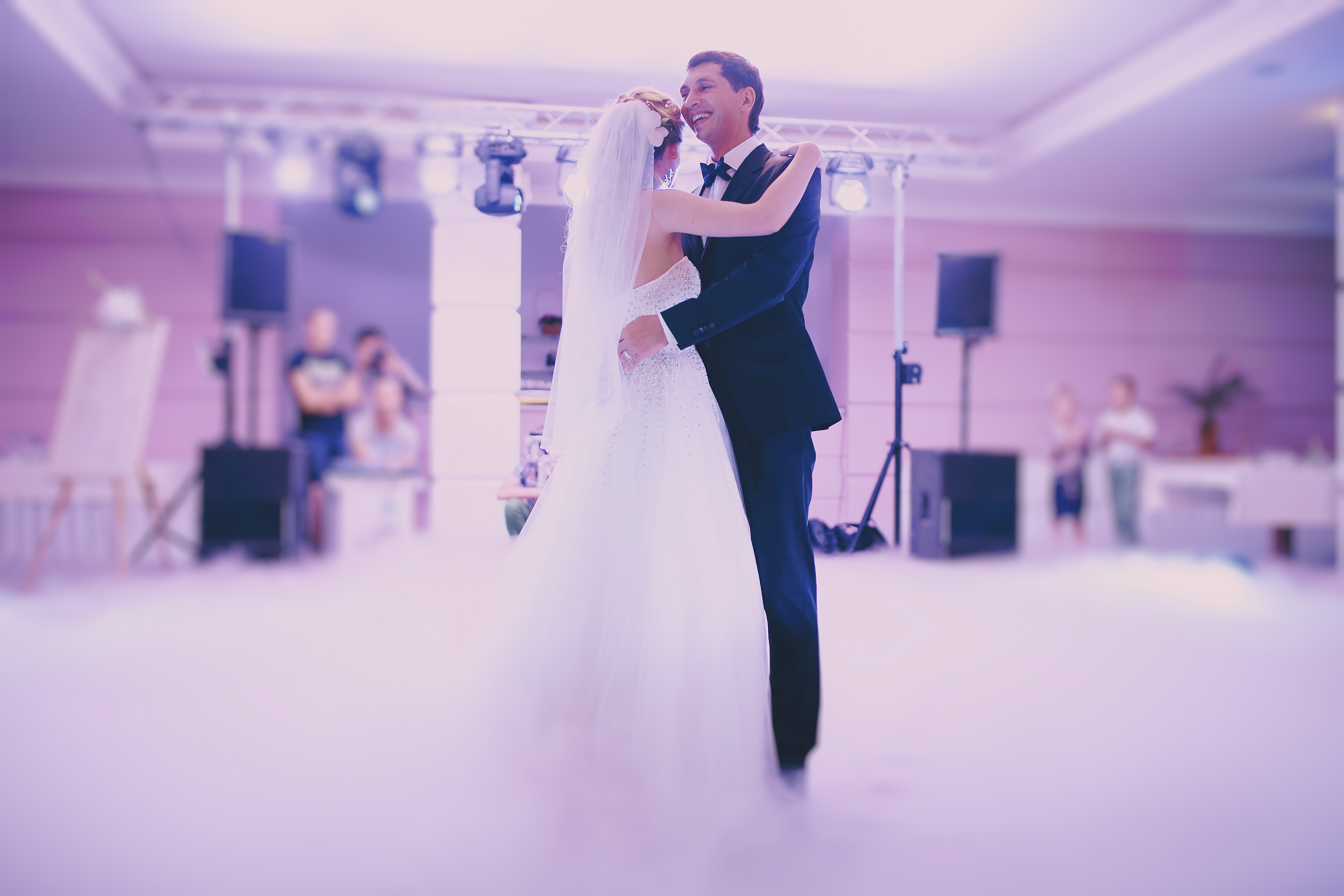 Bride and groom sharing a soft, fog-lit first dance at a wedding reception